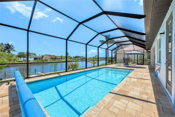 Swimming pool featuring a patio area, a water view, and a lanai