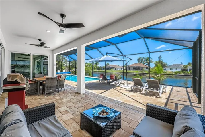 View of patio with an outdoor pool, ceiling fan, screen enclosure, outdoor lounge area, and a water view