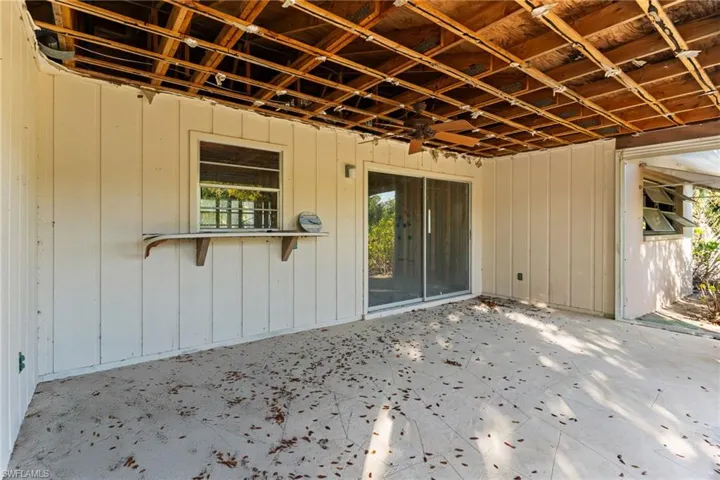 Unfurnished sunroom with a ceiling fan, a water view, and a patio