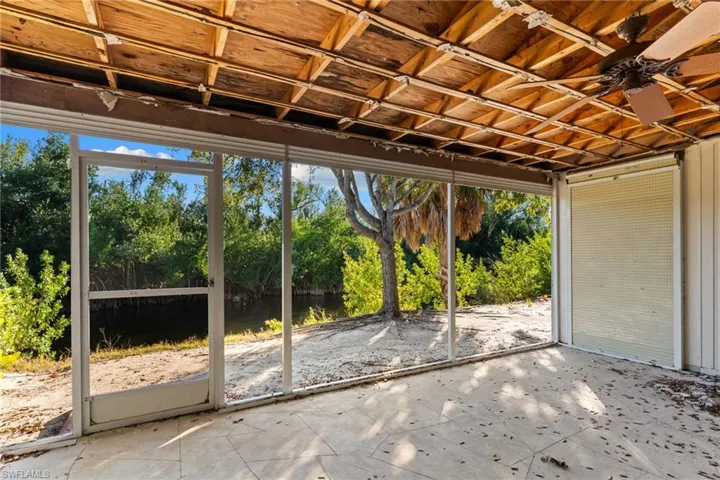 Unfurnished sunroom with a ceiling fan, a water view, and a patio