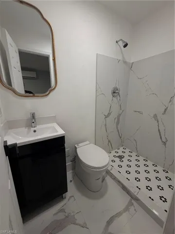 Full bathroom featuring a marble finish shower, vanity, and marble finish flooring