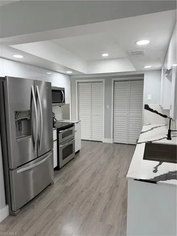 Kitchen with fridge, stove, white cabinetry, light wood-style flooring, and modern cabinets