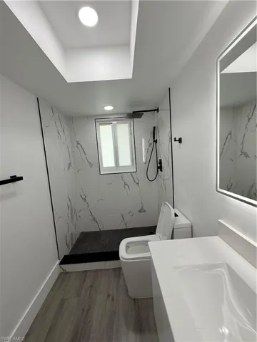 Bathroom with a marble finish shower, wood finished floors, and vanity