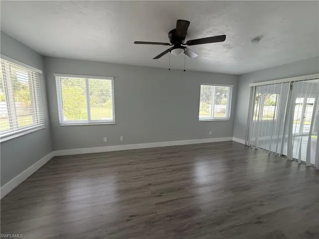 Unfurnished room with dark wood-type flooring, ceiling fan, and a smoke detector