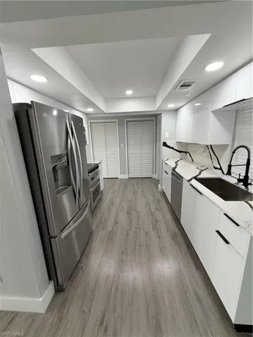 Kitchen featuring modern cabinets, refrigerator, white cabinetry, light wood-style floors, and recessed lighting
