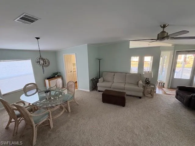 Carpeted living area featuring baseboards, ceiling fan, visible vents, and crown molding