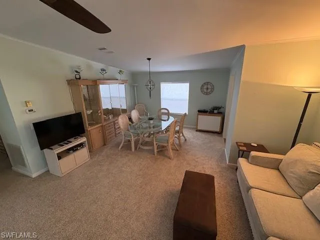 Living room featuring ornamental molding, baseboards, light colored carpet, and visible vents
