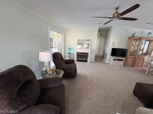 Carpeted living area featuring ornamental molding, ceiling fan, and plenty of natural light