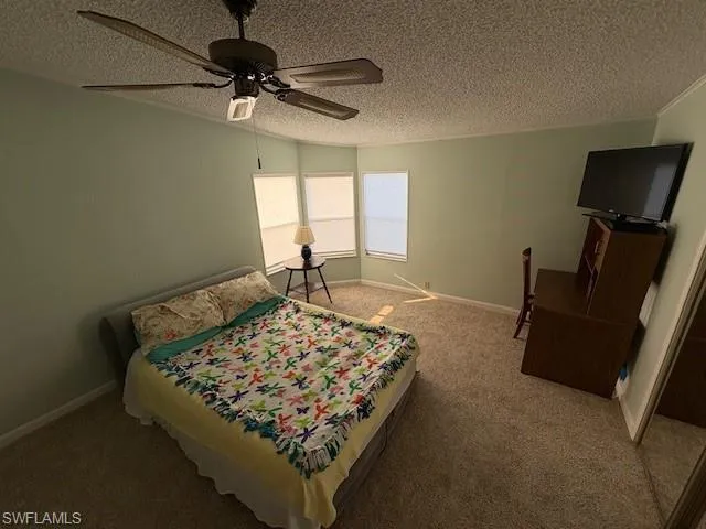 Bedroom with baseboards, a textured ceiling, ceiling fan, and carpet