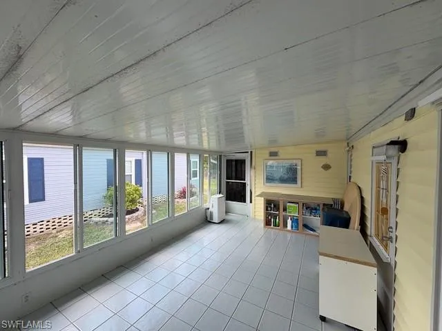 Unfurnished sunroom with tile patterned flooring and wood ceiling