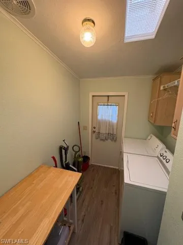 Clothes washing area with crown molding, separate washer and dryer, dark wood-style floors, visible vents, and cabinet space