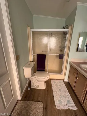 Full bathroom featuring wood finished floors, crown molding, a stall shower, and visible vents