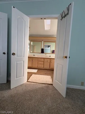 Bathroom featuring double vanity, a sink, baseboards, and carpet floors
