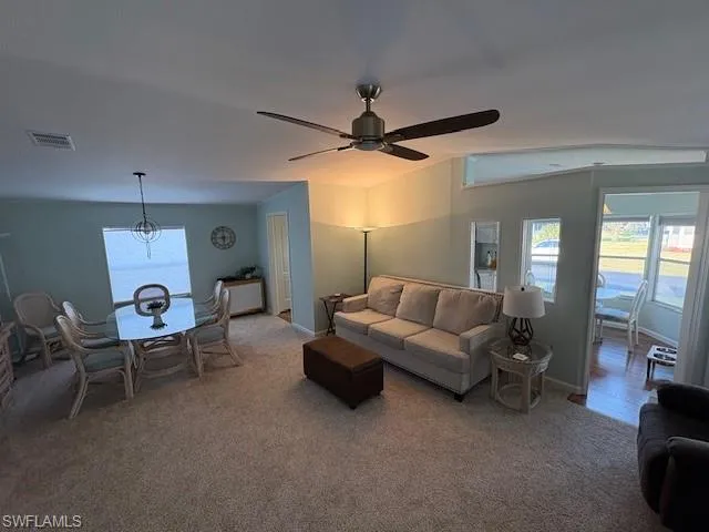 Living room featuring baseboards, ceiling fan, visible vents, and light colored carpet