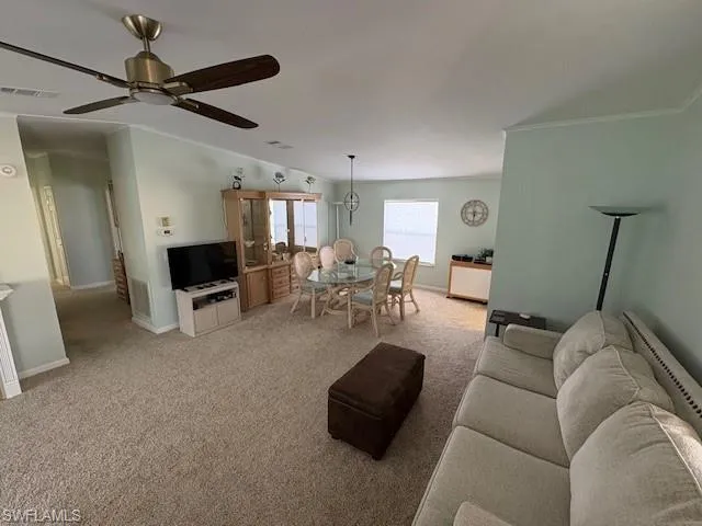 Living area with a ceiling fan, light carpet, baseboards, and visible vents