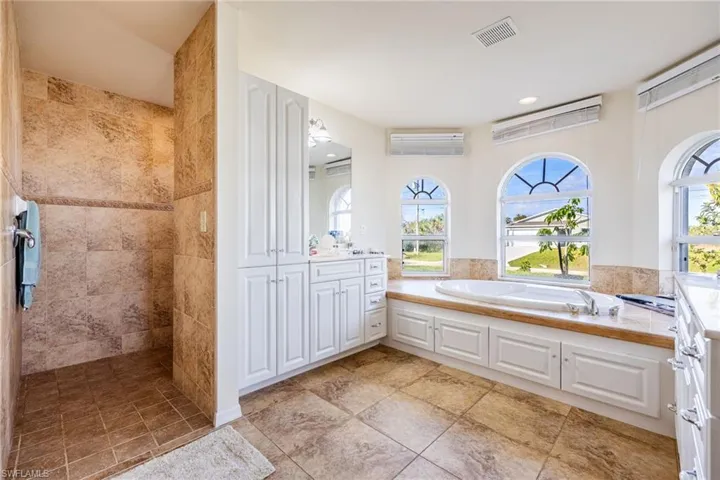 Full bathroom featuring a healthy amount of sunlight, visible vents, a garden tub, and vanity