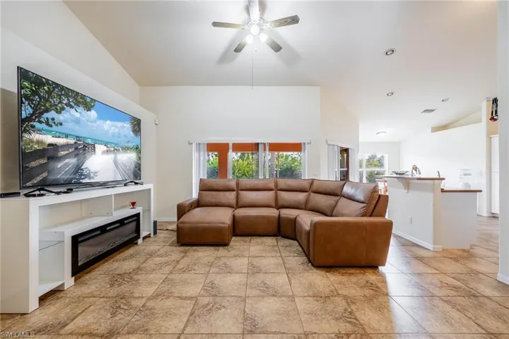 Living area with a ceiling fan, lofted ceiling, and baseboards