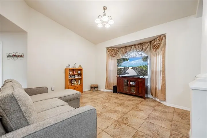 Living area 2 featuring lofted ceiling, an inviting chandelier, and baseboards