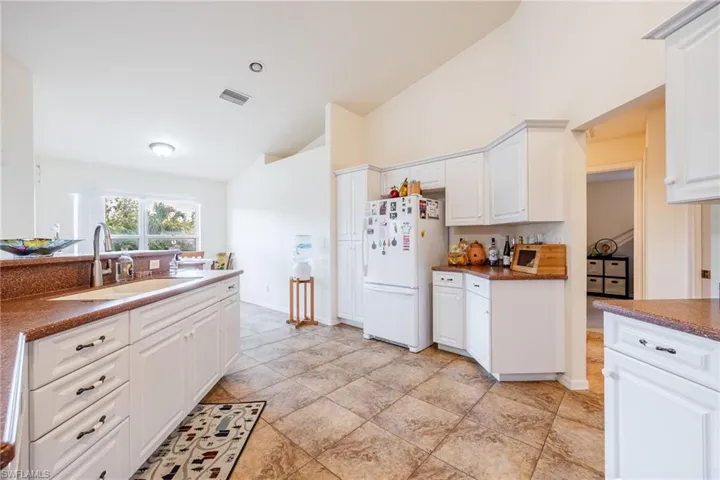 Kitchen with visible vents, dark countertops, freestanding refrigerator, white cabinetry, and a sink