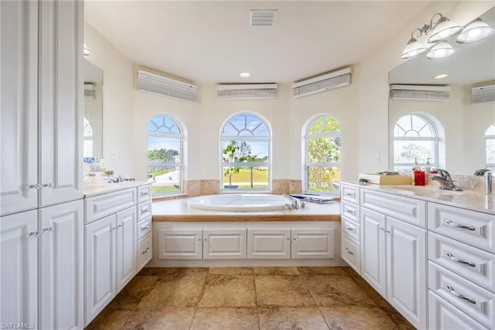 Full bath featuring vanity, a garden tub, and visible vents