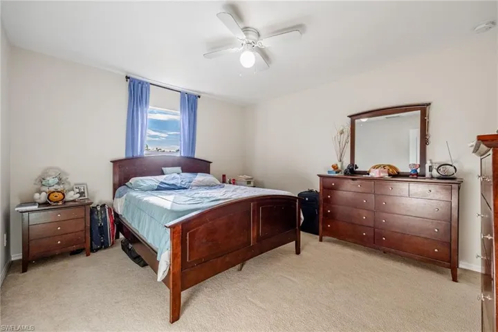 Bedroom featuring a ceiling fan and light colored carpet