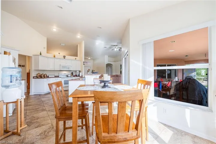 Dining space with vaulted ceiling, arched walkways, and recessed lighting