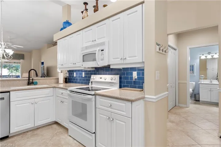 Kitchen with white appliances, white cabinets, and under cabinet lighting.