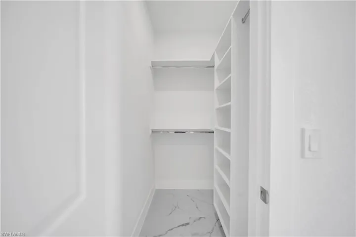 Walk in closet with light marble finish flooring