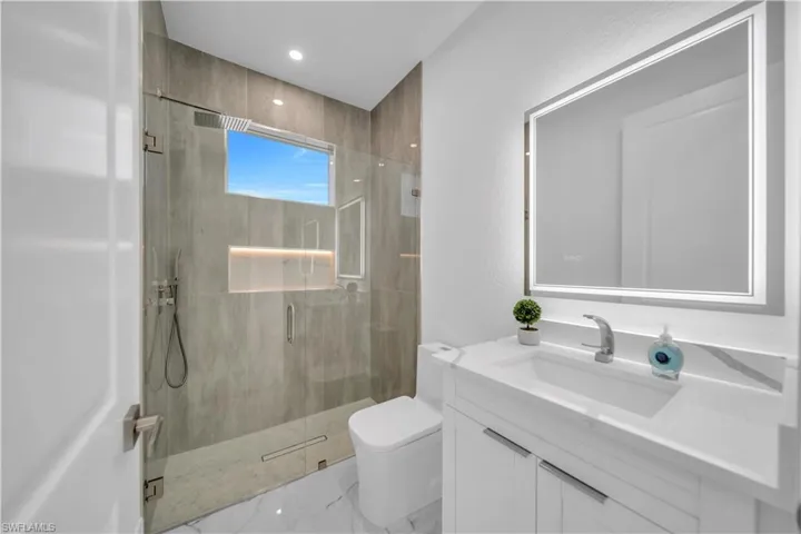 Full bath with vanity, a stall shower, and a textured wall