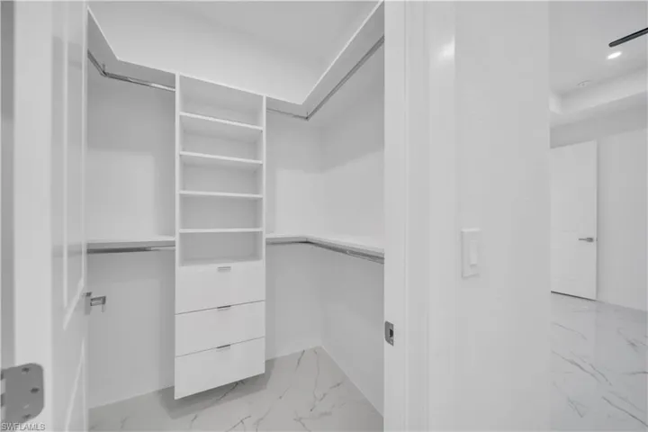 Walk in closet with light marble finish floors
