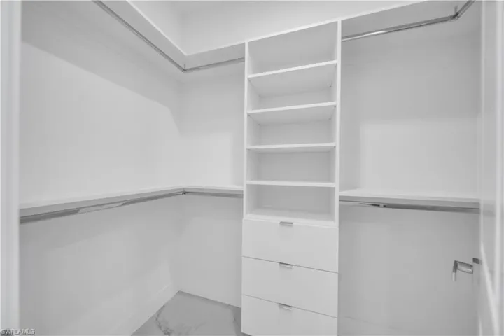 Walk in closet featuring light marble finish floors