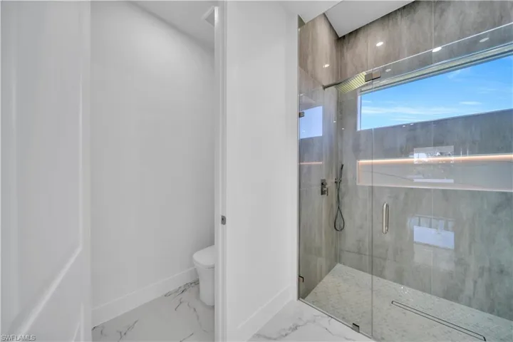 Bathroom featuring a marble finish shower and toilet