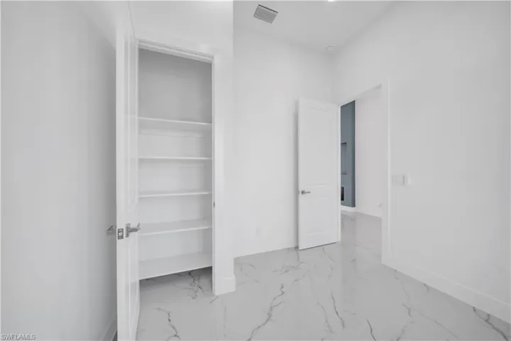 Unfurnished bedroom with light marble finish floors and a closet