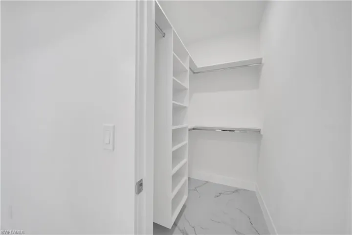 Walk in closet with light marble finish flooring