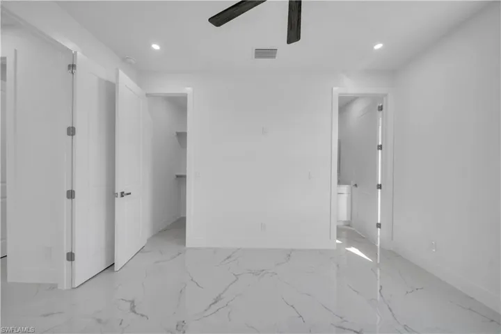 Unfurnished bedroom featuring a spacious closet, recessed lighting, light marble finish floors, and ceiling fan