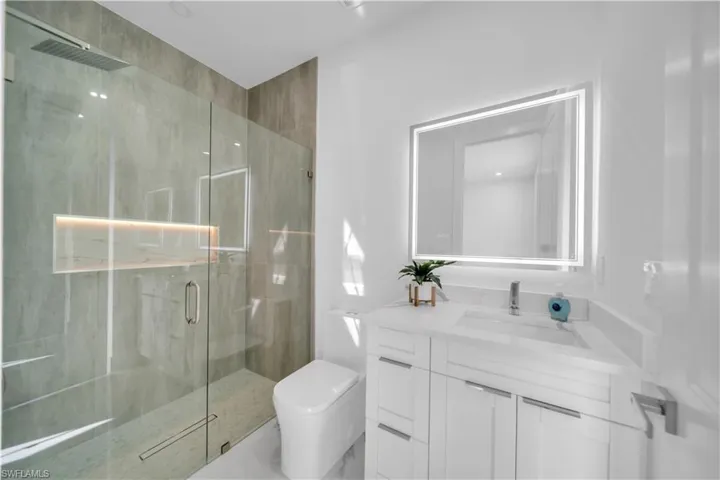 Bathroom with vanity and a marble finish shower