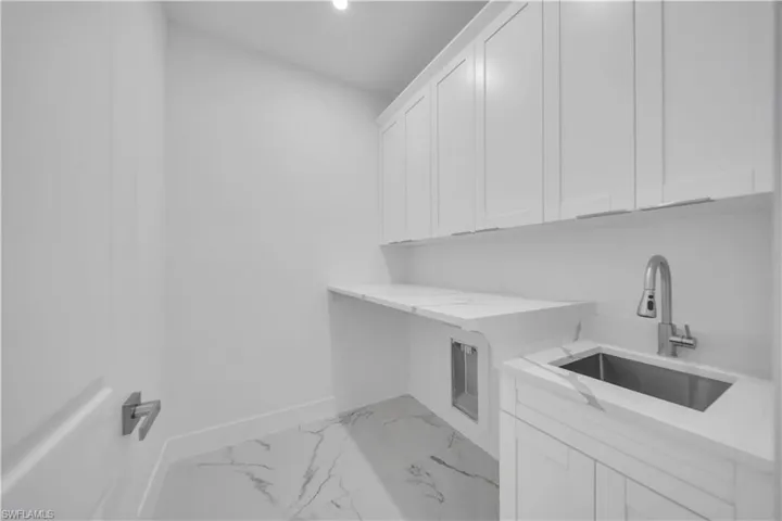 Laundry area with light marble finish flooring, cabinet space, and recessed lighting
