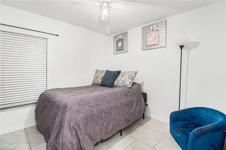 Tiled bedroom featuring ceiling fan and baseboards