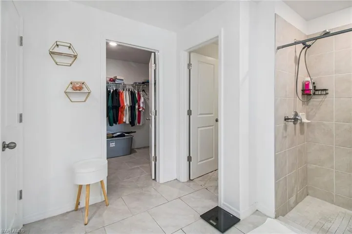 Bathroom featuring a stall shower, a walk in closet, and light tile patterned flooring