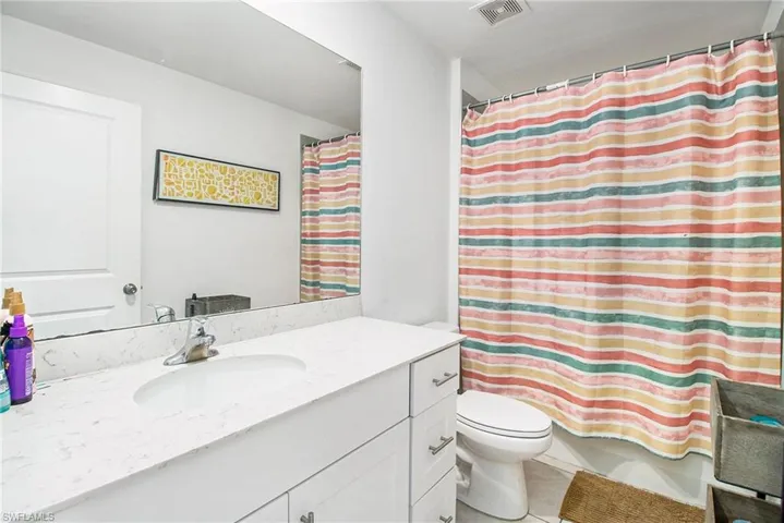 Bathroom with vanity, light tile patterned flooring, and shower / bathtub combination with curtain