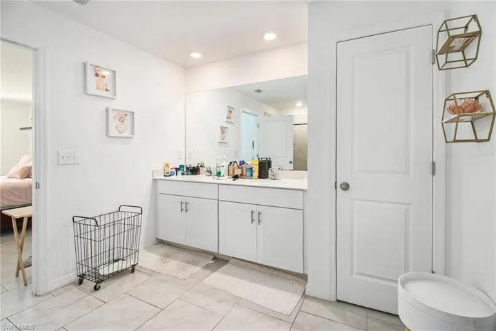 Ensuite bathroom with double vanity, light tile patterned floors, and recessed lighting