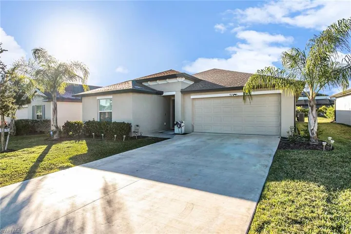 View of front of property with a front lawn, stucco siding, driveway, and roof with shingles