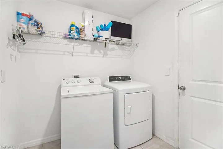 Washroom featuring washing machine and dryer and light tile patterned flooring