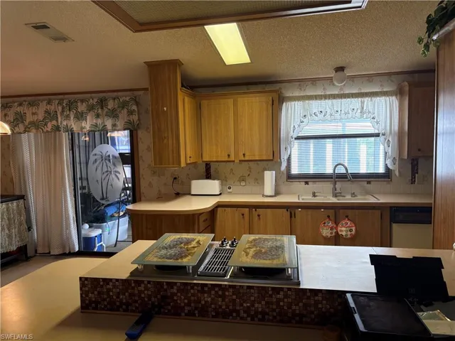 Kitchen with dishwasher, crown molding, sink, and a textured ceiling
