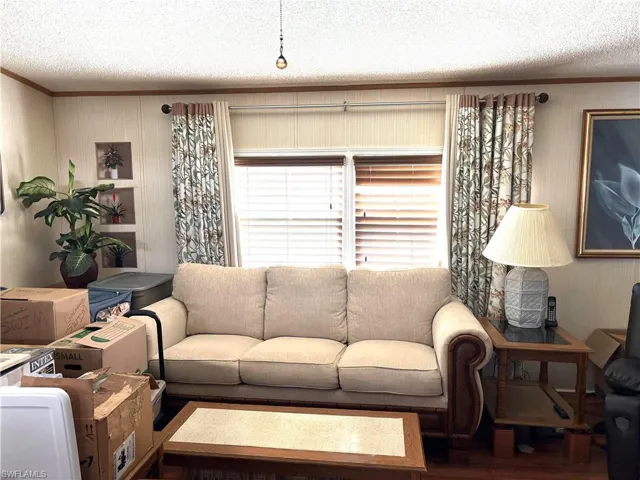 Living room featuring a textured ceiling, crown molding, and hardwood / wood-style floors