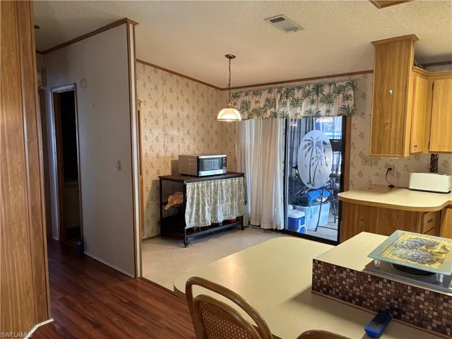 Kitchen featuring pendant lighting, a textured ceiling, dark hardwood / wood-style floors, and crown molding