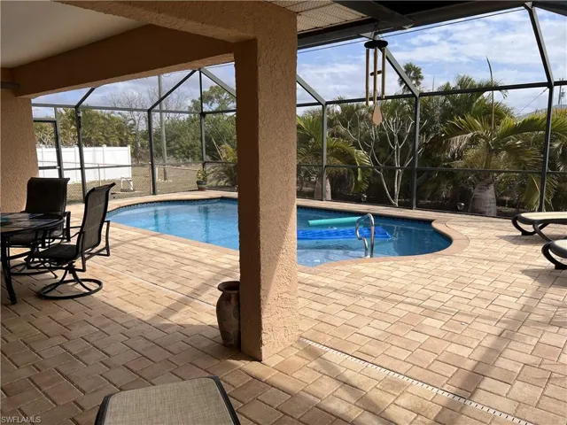 Outdoor pool featuring a sunroom, a patio, glass enclosure, and outdoor dining area