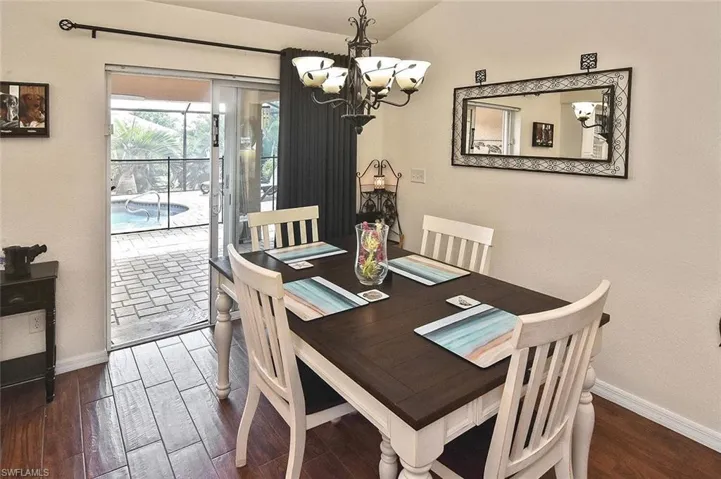 Dining room with wood-style floors, a chandelier, and lofted ceiling