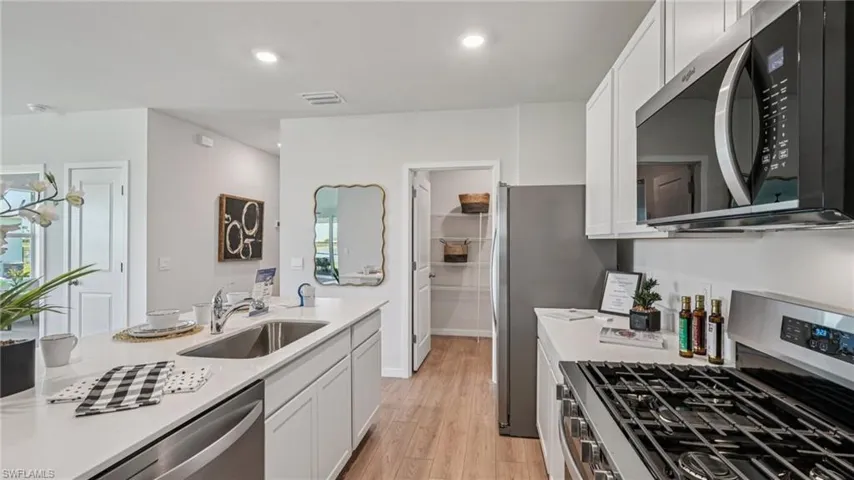 Inside of the kitchen. Stainless steel appliances, quartz countertops, walk-in corner pantry.