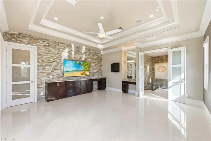 Another view of main bedroom showing dresser space,makeup niche ,french doors and extensive stonework walls